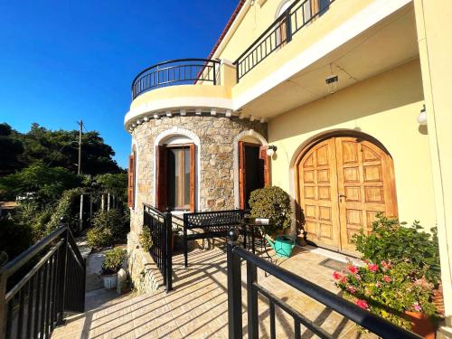 ein Haus mit einer Holztür und einer Bank auf einer Veranda in der Unterkunft Litani Villa in Raches