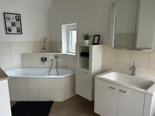 a white bathroom with a tub and a sink at Gästehaus in Titz 