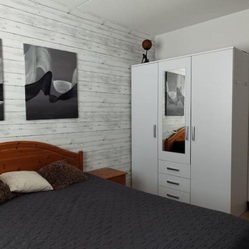 a bedroom with a bed and a white cabinet at Scandinavian taiteilijan 3h huoneisto in Lahti