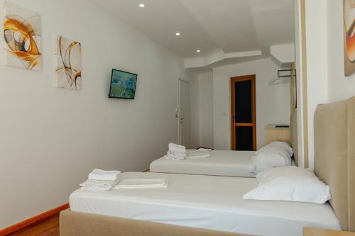 two beds in a room with white walls at Hotel Summer in Sarandë