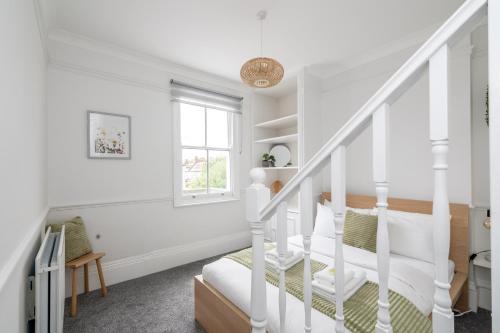 a white room with a bed and stairs at Spacious 3 BR house wParking & Garden, Wimbledon in New Malden