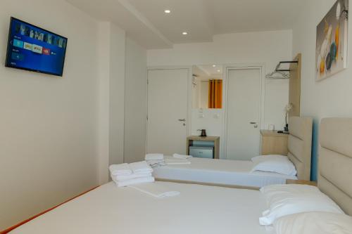 a white room with two beds and a tv at Hotel Summer in Sarandë