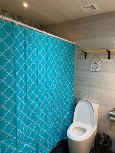 a bathroom with a toilet and a blue tiled wall at Modern Beachfront Getaway at Canyon Cove Nasugbu in Nasugbu