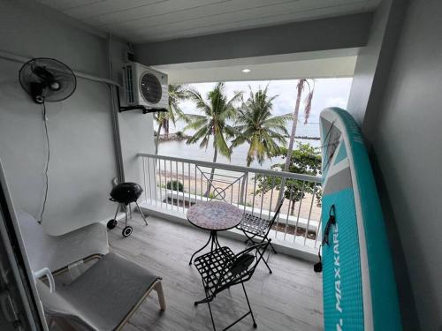 a room with a balcony with a table and a surfboard at Modern Beachfront Getaway at Canyon Cove Nasugbu in Nasugbu