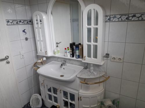 uma casa de banho branca com um lavatório e um espelho em Trochtelfingen F1 em Trochtelfingen