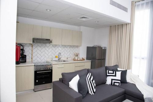 ein Wohnzimmer mit einem Sofa und einer Küche in der Unterkunft Tamm - Luxe Condo With Balcony and Incredible City Views in Dubai