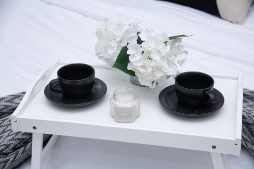 a table with two cups and a candle and flowers at Tamm - Luxe Condo With Balcony and Incredible City Views in Dubai