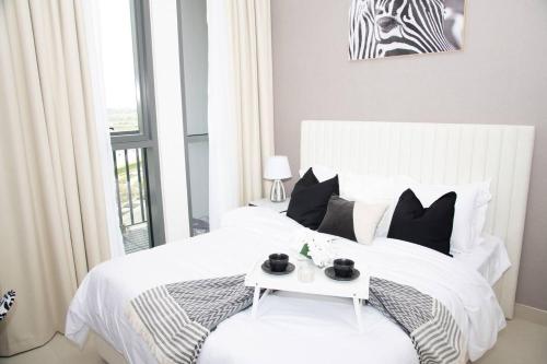 ドバイにあるTamm - Luxe Condo With Balcony and Incredible City Viewsのベッドルーム(白いベッド、テーブル付)