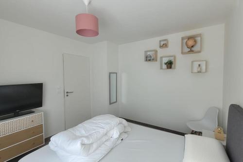 Cette chambre blanche dispose d'un lit et d'une télévision. dans l'établissement Maison avec jardin sur Berck, à Berck-sur-Mer