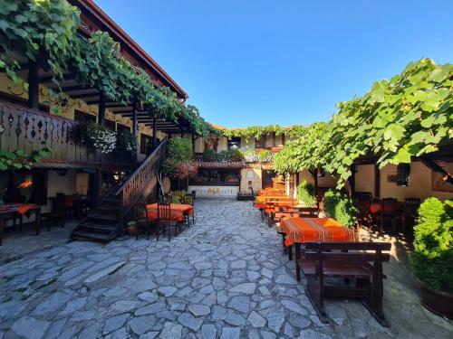 a patio with tables and chairs in a building at Стаи за гости The Old House in Velingrad