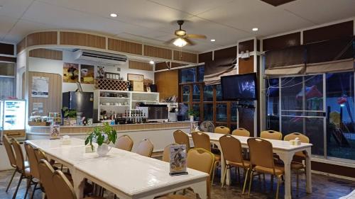 um restaurante com mesas e cadeiras e uma cozinha em Uthai River Lake Resort em Ban Nong Nam Khan