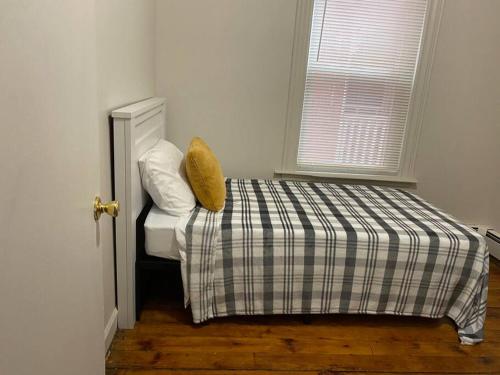 a bedroom with a bed with a plaid blanket and a window at Frog Hollow Red Door Haven in Hartford