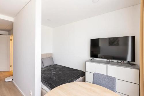 a small room with a bed and a flat screen tv at Ozo eco apartments in Vilnius