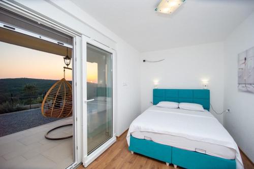 a bedroom with a blue bed and a balcony at Sunset house in Višnjevo