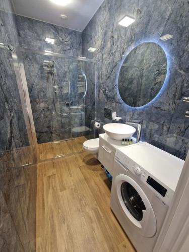 ein Badezimmer mit einer Dusche, einem Waschbecken und einer Waschmaschine in der Unterkunft DeMar Apart STAR in Lwiw