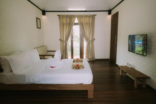 una camera con un letto bianco e una finestra di The Kelong Trikora Resort a Kangkakawal