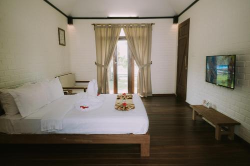 a bedroom with a white bed and a window at The Kelong Trikora Resort in Kangkakawal