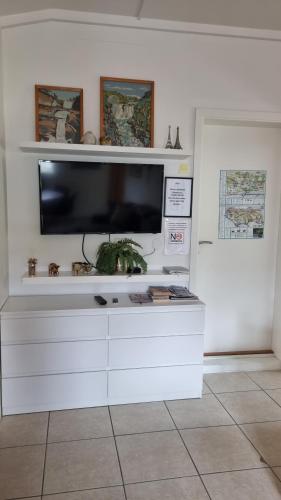 a white entertainment center with a flat screen tv on a wall at Guesthouse Galleri Vík in Vík