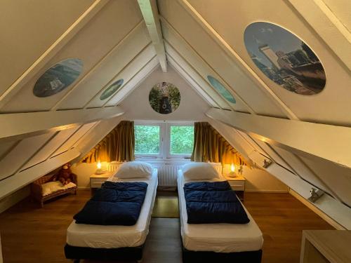a attic room with two beds and two windows at Butterflies, bungalow 134 in Simpelveld