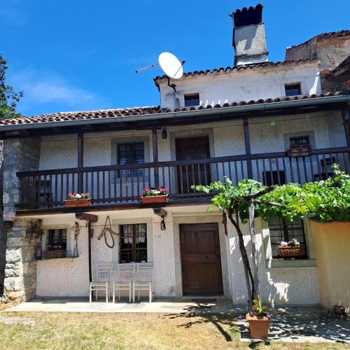 an old house with a balcony and two chairs at Holiday house Luin in Komen