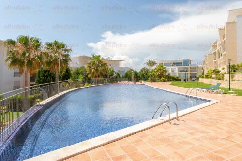 a swimming pool in a villa with palm trees and buildings at Encosta da Orada By Albufeira Rental in Albufeira