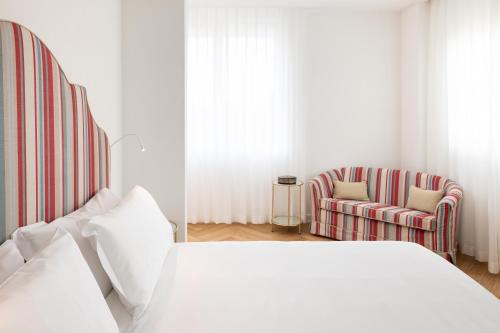a white bedroom with a bed and a chair at Hotel Morfeo in Milan