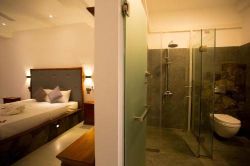 y baño con cama y ducha acristalada. en Lena Resort, en Beruwala
