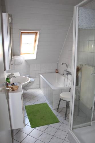 Baño blanco con bañera y lavamanos en Ferienwohnung Schmetterling, en Trendelburg