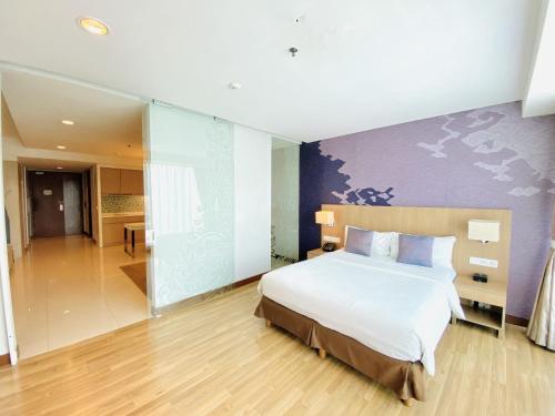a bedroom with a large bed and a hallway at The H Tower Rasuna Suites Kuningan Jakarta By Villaloka in Jakarta