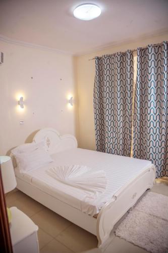 a white bed in a room with a curtain at RIVER APPARTS in Brazzaville