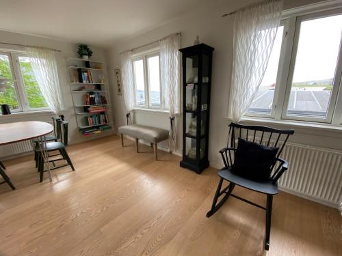 a living room with a table and chairs and windows at 1 Bedroom Home - Private Balcony - Parking On Site in Tórshavn
