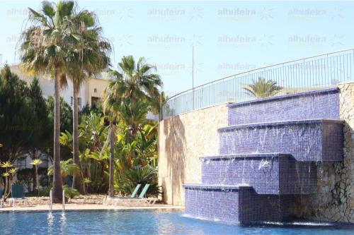 a resort with a swimming pool with palm trees at Encosta da Orada By Albufeira Rental in Albufeira