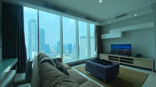 a living room with a couch and a flat screen tv at The H Tower Rasuna Suites Kuningan Jakarta By Villaloka in Jakarta