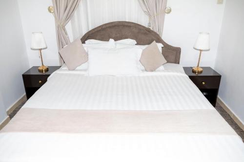a bedroom with a large white bed with two night stands at غزالي للوحدات السكنية in Al Madinah