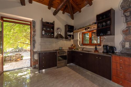 una cocina con armarios de madera y una puerta abierta en PRINOS GARDEN, en Farsáron