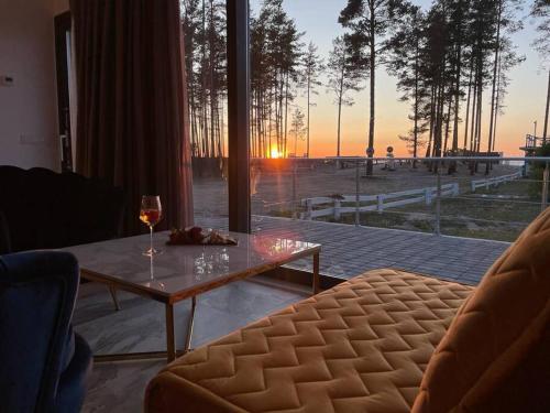 a living room with a table and a glass of wine at Valkla Puhkekeskus - Merevaatega SVIIT in Salmistu