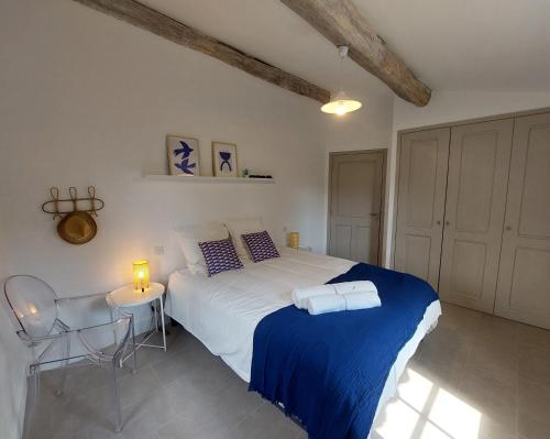 une chambre avec un lit avec une couverture bleue et une table dans l'établissement La petite maison, à Châteauneuf