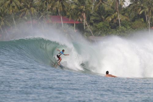 Ein Mann reitet eine Welle auf einem Surfbrett im Ozean in der Unterkunft Endi Surf Camp in Lagudri