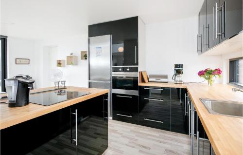a kitchen with black cabinets and a stainless steel refrigerator at Three-Bedroom Holiday Home In Lokken in Løkken