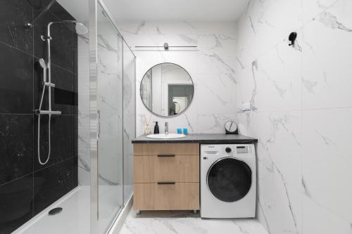 a bathroom with a washing machine and a mirror at Blue Morpho Piątkowo Apartment in Poznań