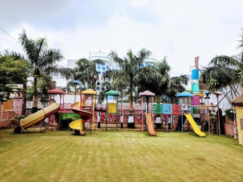 a playground with slides in a park with palm trees at Heritage Hotel in Lucknow