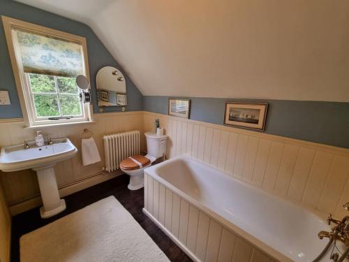 ein Badezimmer mit einer Badewanne, einem Waschbecken und einem WC in der Unterkunft Smugglers Cottage in Barton on Sea