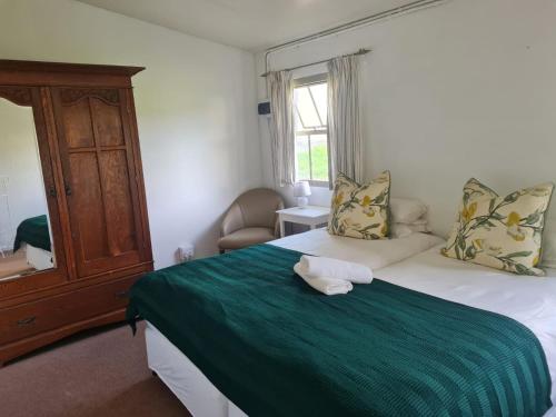 Oak Lane Cottages في إلغين: غرفة نوم مع سرير مع بطانية خضراء وخزانة