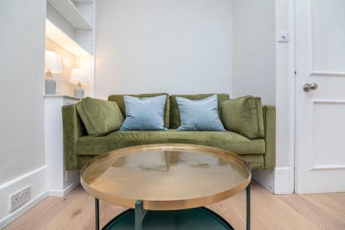 sala de estar con sofá verde y mesa de cristal en Stylish first floor 1BR flat in Notting Hill, en Londres