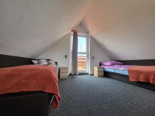 sypialnia na poddaszu z 2 łóżkami i oknem w obiekcie Ośrodek Wypoczynkowy Słoneczny Brzeg w mieście Rzeszów