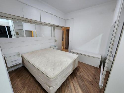 a white bedroom with a bed and a mirror at Apê Pé na Areia 3quartos/2vagas in São Vicente