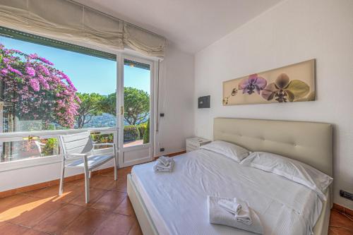 ein Schlafzimmer mit einem Bett und einem großen Fenster in der Unterkunft Villa Orchidea by PortofinoHomes in Santa Margherita Ligure