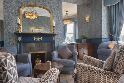 a living room with a fireplace and chairs and a mirror at The Lansdowne, Eastbourne in Eastbourne