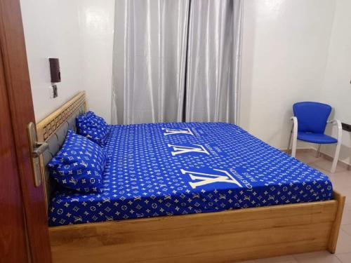 1 cama con edredón azul y silla azul en Meublés en Cotonú
