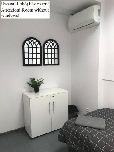 a bedroom with a bed and a white cabinet with a plant on it at Aleja "Solidarności" in Warsaw